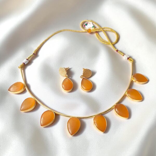 Orange Monalisa Stone Brass Hasli Set with teardrop-shaped Monalisa stones, gold-plated brass hasli, matching earrings and adjustable thread closure.