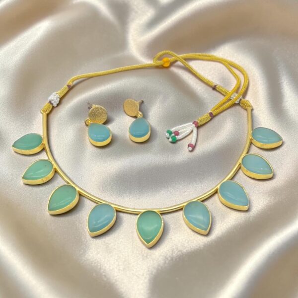 Sky Blue Monalisa Stone Brass Hasli Set with teardrop-shaped Monalisa stones, gold-plated brass hasli, matching earrings and adjustable thread closure.